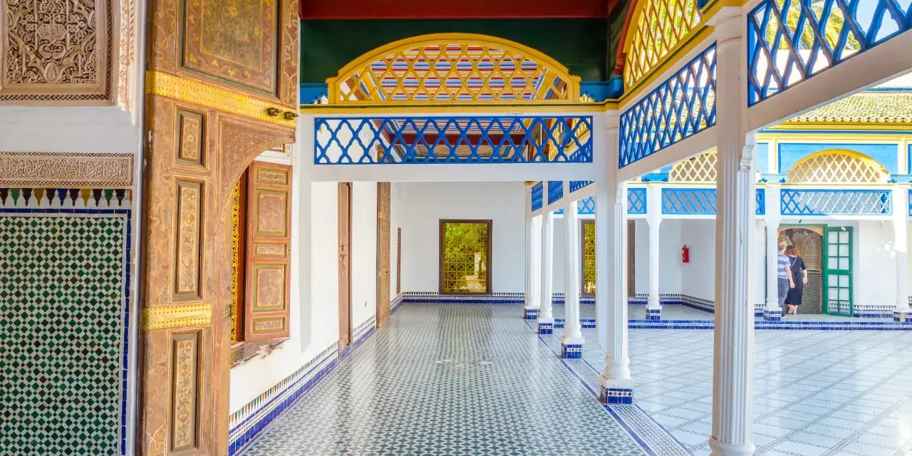 Kolorowy dziedziniec w Maroko, Marrakesz. Wzory geometryczne na ścianach i podłodze, zdobione drzwi i kolorowy sufit.