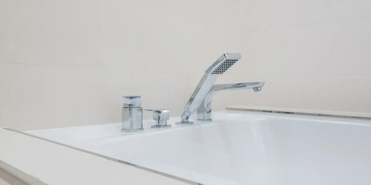 Elegancka bateria wannowa jednootworowa z chromowanymi elementami i słuchawką prysznicową, idealna do nowoczesnej łazienki.