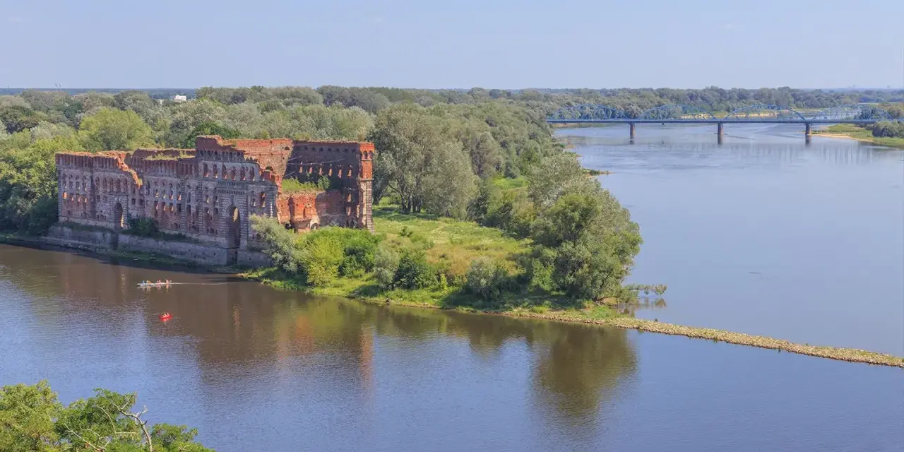 Ruiny twierdzy nad Wisłą, gdzie można poczuć się jak w górach, choć to nie są jakie góry są najbliżej Warszawy. W oddali błękitny most.
