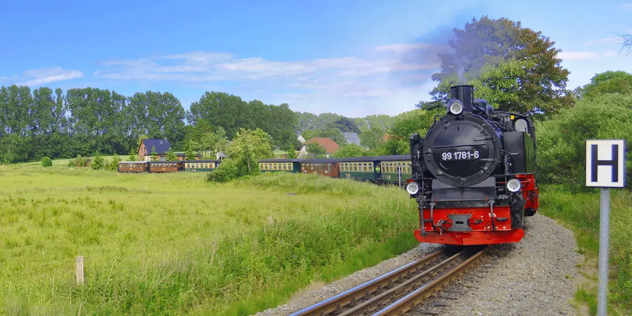 Parowóz z wagonami jedzie przez zielone pola, jakby to był dojazd z Polski do Rugii.