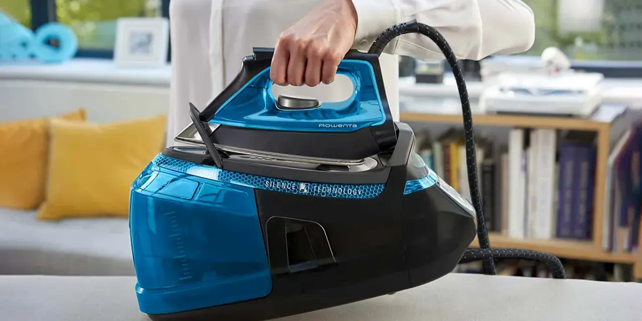 Mano che solleva un ferro da stiro moderno blu e nero, con serbatoio trasparente e tecnologia Silence.