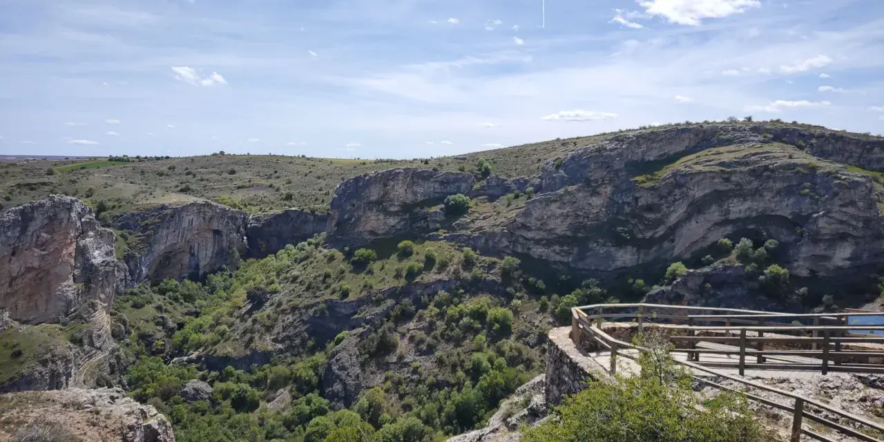 Impresionante vista del **barranco del Río Dulce**, con sus paredes rocosas, vegetación exuberante y un mirador de madera.