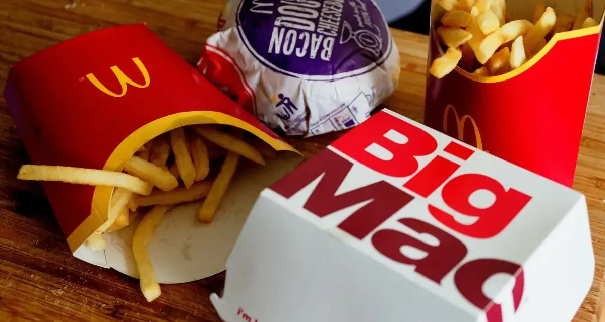 Frytki McDonald's w czerwonych opakowaniach i pudełko Big Mac na drewnianym tle.