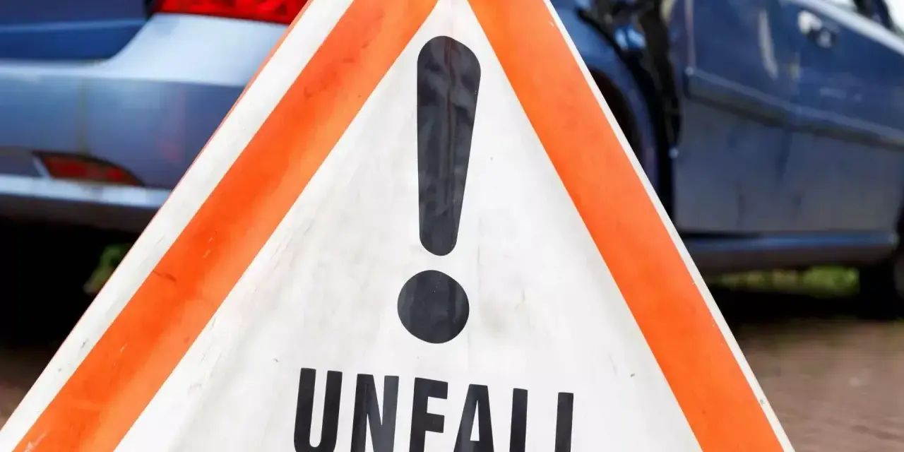 Warnschild "Unfall" vor beschädigtem Auto. Nach einem Verkehrsunfall kann eine Vorstandsbeschwerde bei der Versicherung nötig sein.