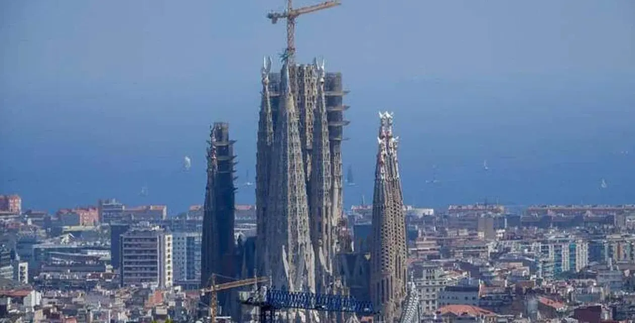 La Sagrada Familia, en plein temps de construction, domine le paysage urbain de Barcelone. Des grues témoignent de l'évolution de ce chef-d'œuvre architectural.