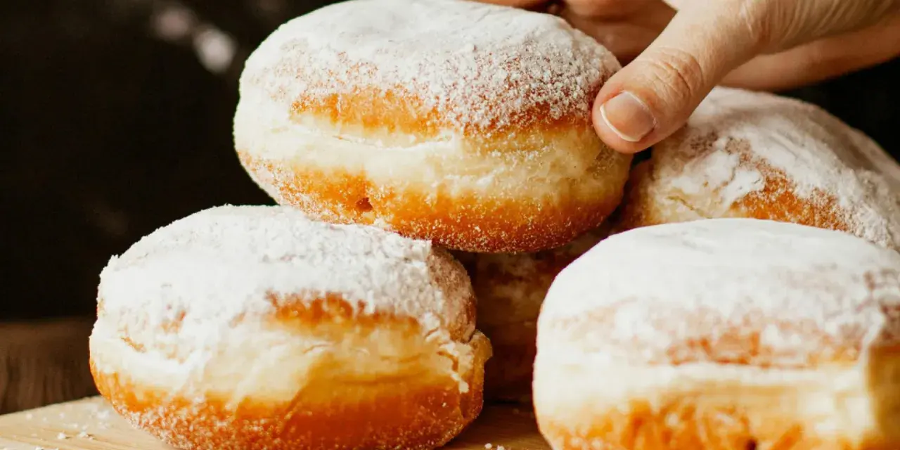 Stos puszystych pączków oprószonych cukrem pudrem. Idealne na tłusty czwartek, te fit pączki kuszą apetycznym wyglądem.
