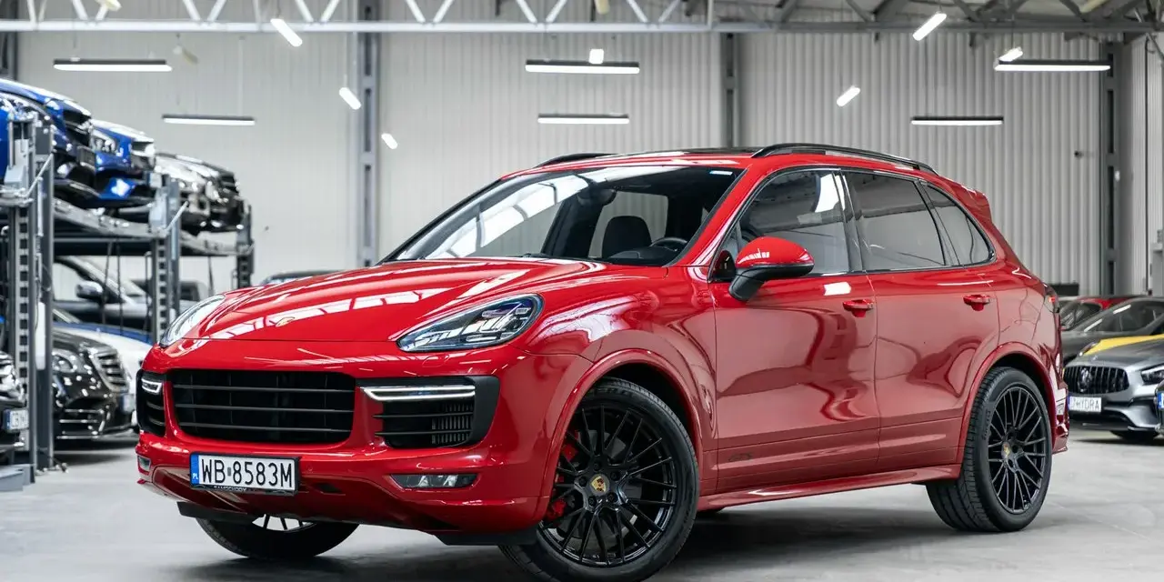 Czerwony Porsche Cayenne GTS lśni w salonie, gotowy na podbój dróg.