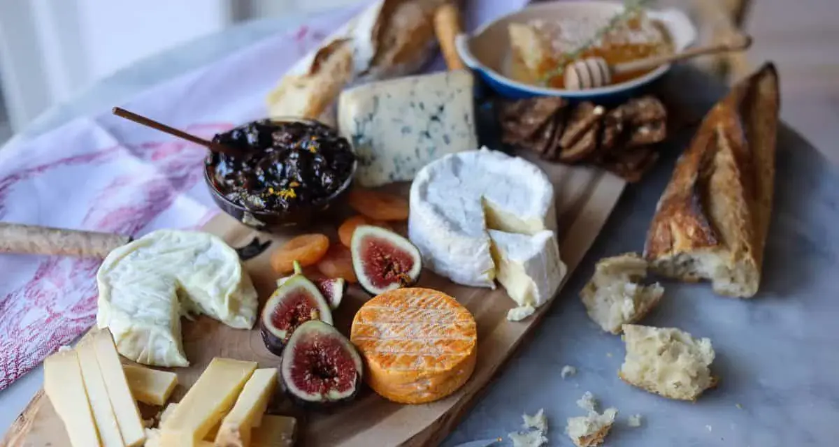 Plateau de fromages variés, dont un fromage à pâte cuite, avec figues, confiture et pain.