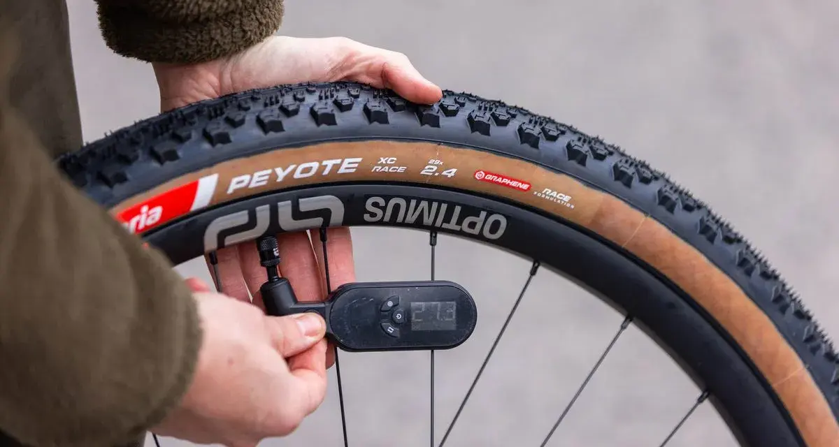 Checking the mountain bike tire pressure with a digital gauge. The tire reads 27.3 PSI.