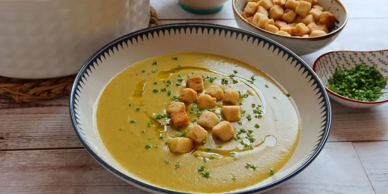 Un cremoso puré de verduras, adornado con picatostes crujientes y un chorrito de aceite de oliva.