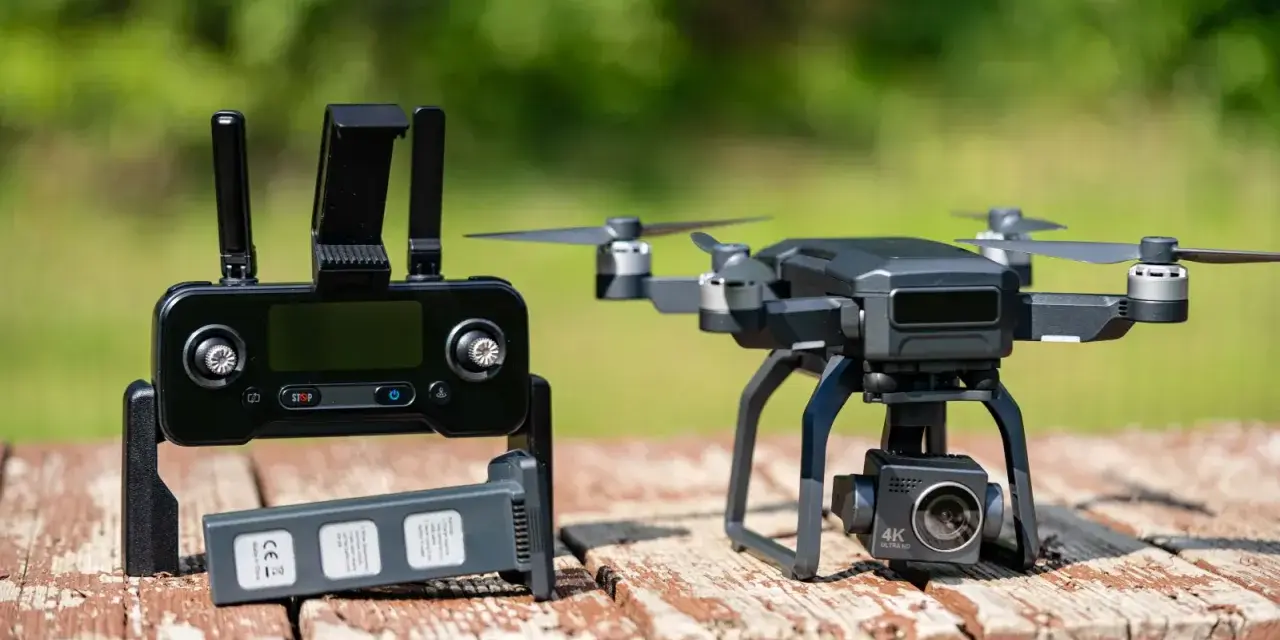 A drone with a 4K camera sits on a wooden table next to its controller and a spare battery, ready for its next follow drone adventure.