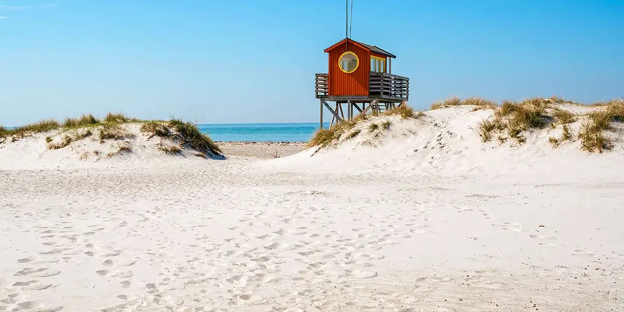 Piękne plaże w Szwecji z charakterystyczną czerwoną wieżą ratowniczą na wydmach.