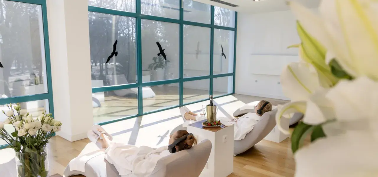 Relaks w spa, idealne **ciechocinek atrakcje na weekend**. Dwie kobiety w szlafrokach odpoczywają na leżakach, słuchając muzyki.