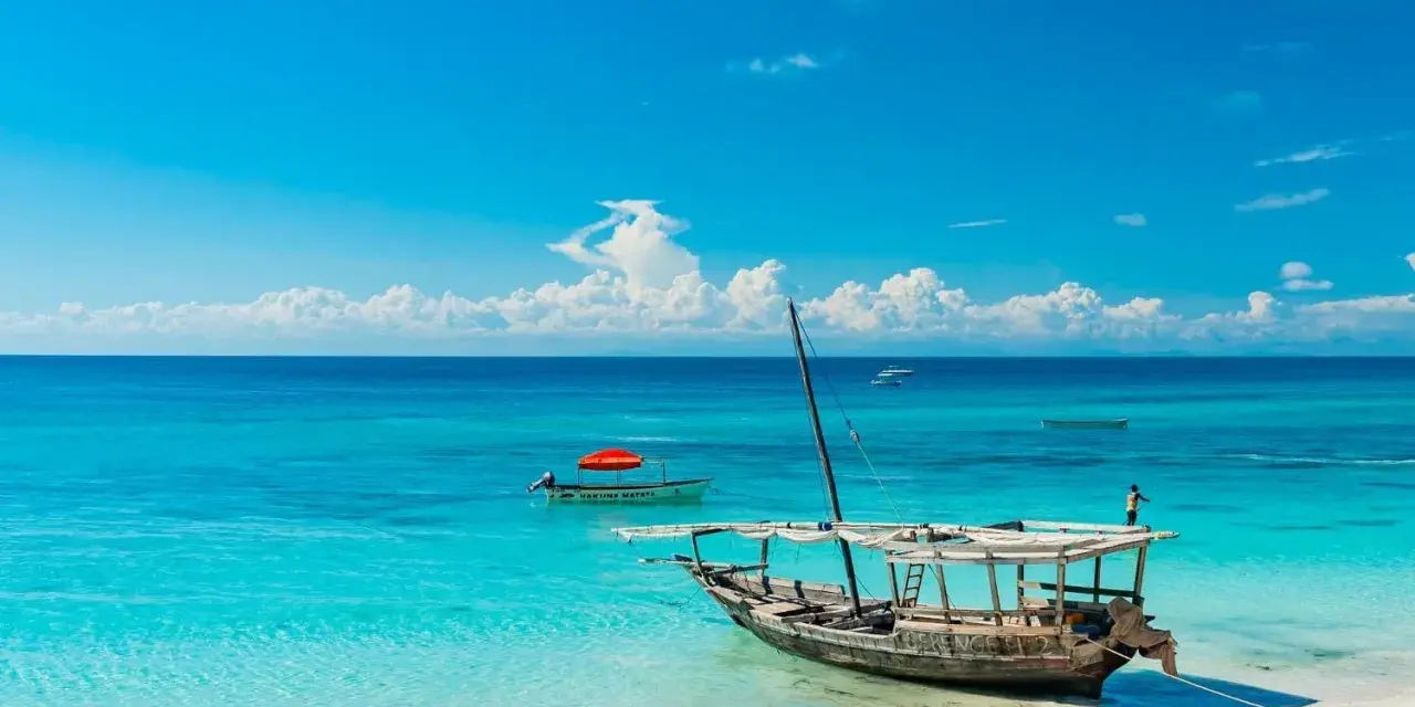 Piękna plaża na Zanzibarze, turkusowa woda, łodzie i marzenia o wakacjach. Może nawet o zarobieniu tam zanzibar dolary.