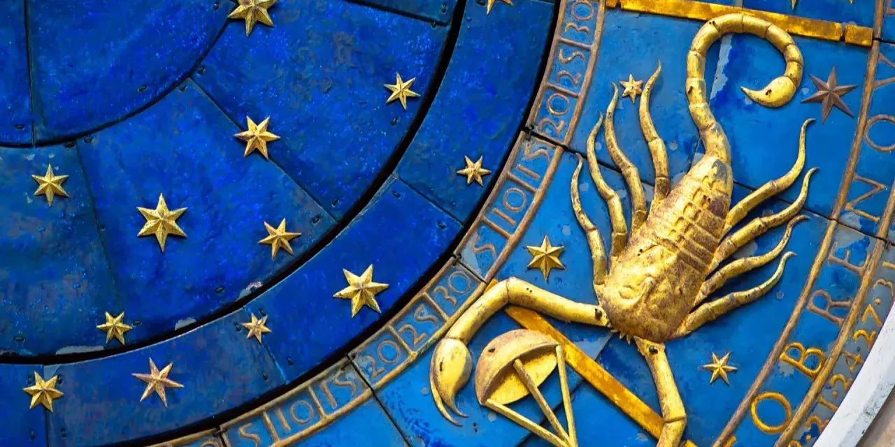Złoty skorpion, symbol zodiaku, na niebieskiej tarczy z gwiazdami i cyframi.