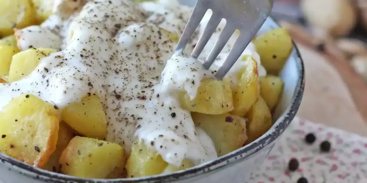 Ziemniaki w kremowym sosie z pieprzem, inspirowane przepisem Cacio e Pepe. Widok z bliska na widelec nabijający ziemniaka.