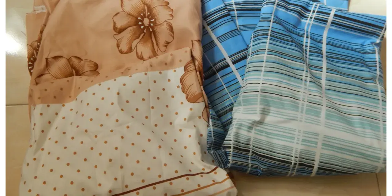 Tissus pliés, un à fleurs beiges et pois, l'autre à rayures bleues. Idéal pour apprendre comment faire un drap housse.