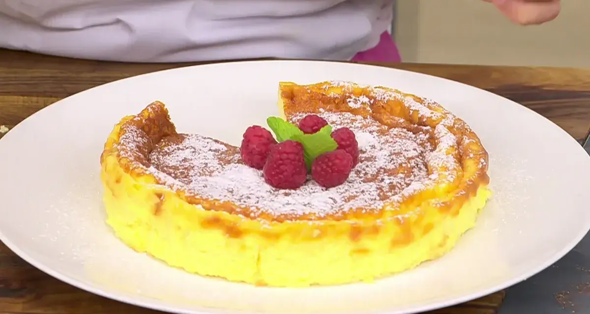 Tarta de queso Arguiñano recién horneada, espolvoreada con azúcar glas y decorada con frambuesas y menta.