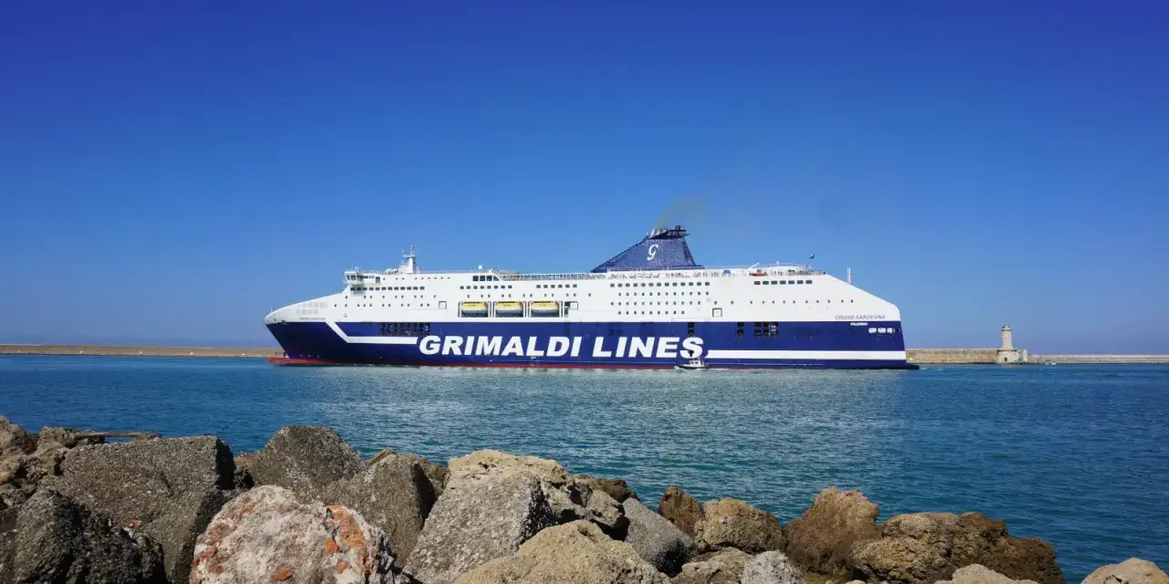 Prom Grimaldi Lines wypływa z Livorno do Palermo. Statek "Cruise Sardegna" na tle błękitnego nieba i morza.