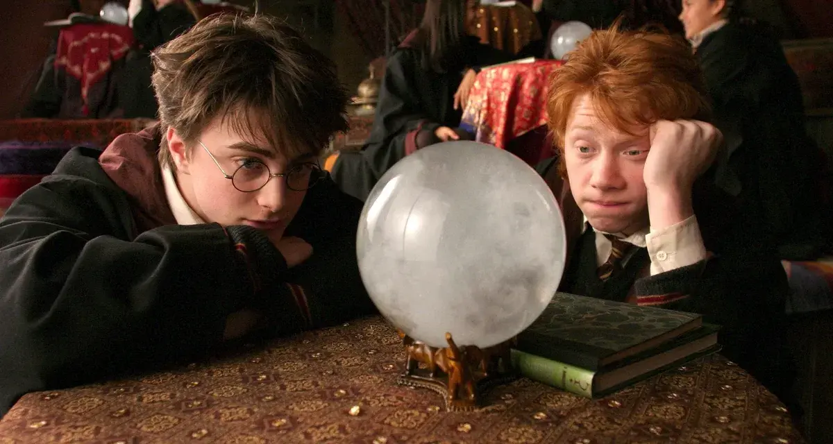 Harry i Ron wpatrują się w wirującą mgłę kryształowej kuli, która mówi, szukając odpowiedzi na lekcji wróżbiarstwa.