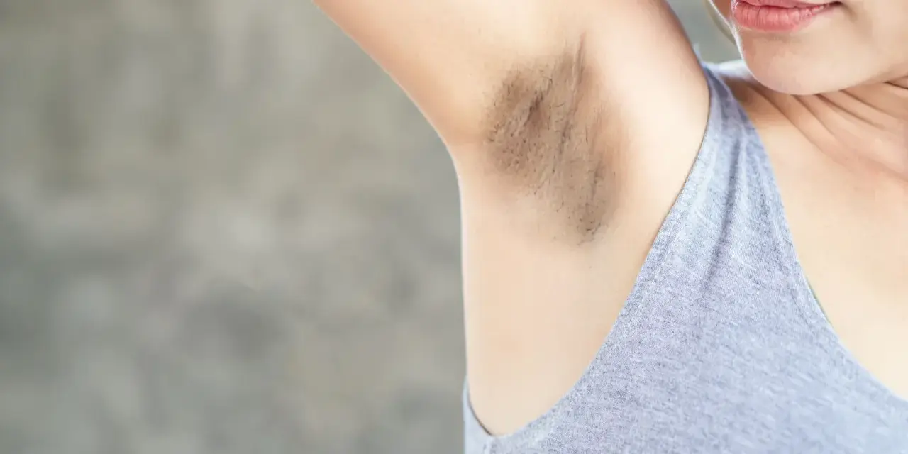 Primer plano de una axila con manchas oscuras y vello visible.
