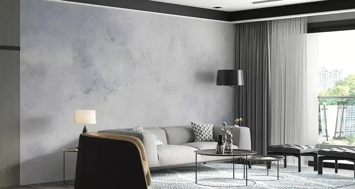 Nowoczesny salon z sofą, stolikami i dywanem. Ściana za sofą ma subtelny **efekt betonu**, nadając wnętrzu industrialny charakter.