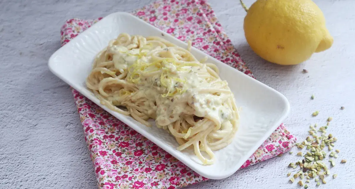 Spaghetti al limone cremosi, un piatto invitante con scorza di limone grattugiata e pistacchi tritati.