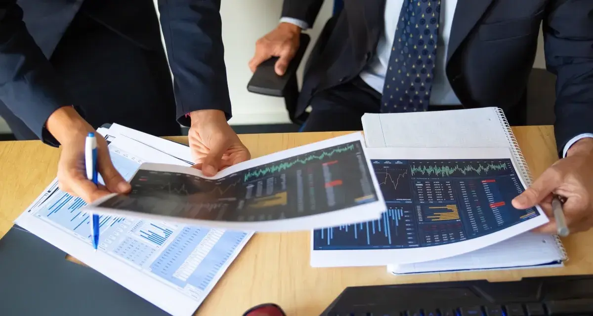 Dos personas analizan gráficos financieros, discutiendo los diferentes tipos de auditorías y sus implicaciones para el negocio.