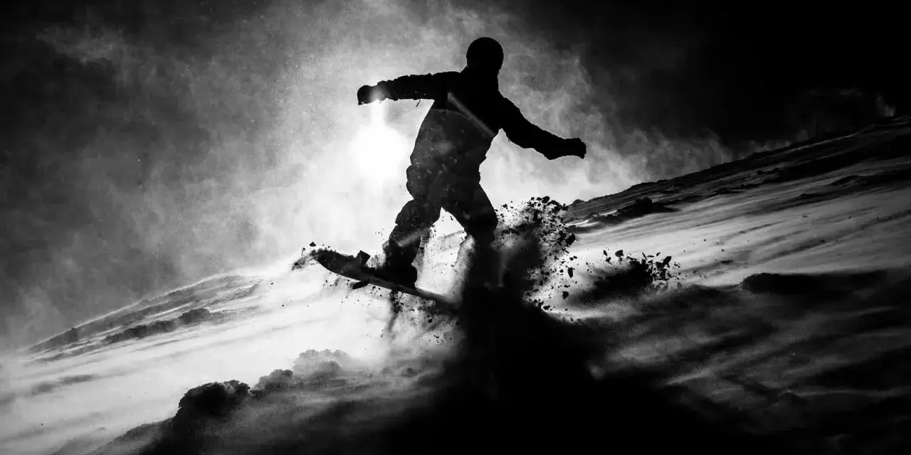 Une silhouette de snowboarder en plein saut, projetant de la neige. L'image, une peinture sur toile noire, capture l'énergie du mouvement dans un style dramatique.