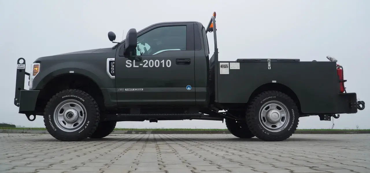 Ciemnozielony Ford F350 z zabudową typu "flatbed" i numerem SL-20010. Solidna maszyna gotowa do pracy.