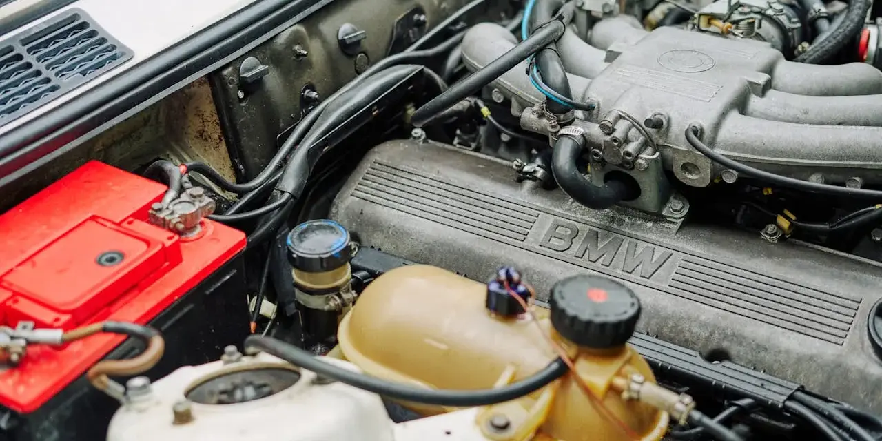 Silnik BMW 1.6 mpi z widocznym akumulatorem i zbiorniczkiem płynu.
