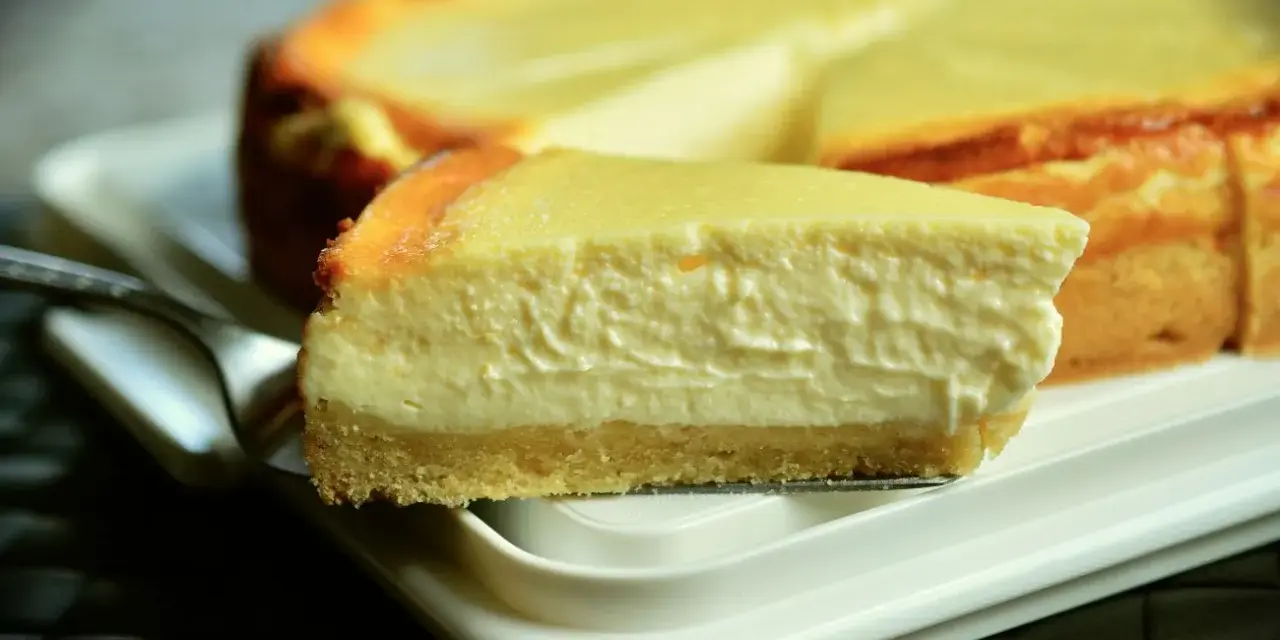 Una rebanada cremosa de tarta de queso Philadelphia, con su base dorada y relleno suave, lista para ser disfrutada.