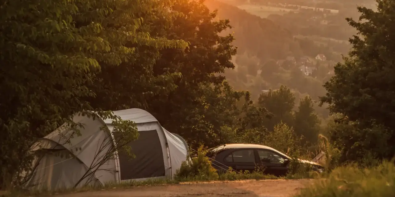Namiot i samochód na tle malowniczego krajobrazu o zachodzie słońca. Idealne miejsce na **camping Kraków**.