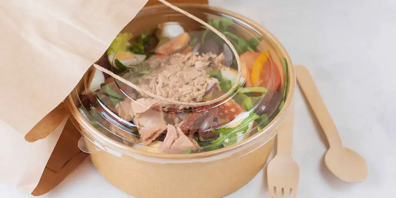 Ensalada de atún para llevar, con ingredientes frescos y cubiertos en un recipiente ecológico. Perfecta para tu licencia take away.