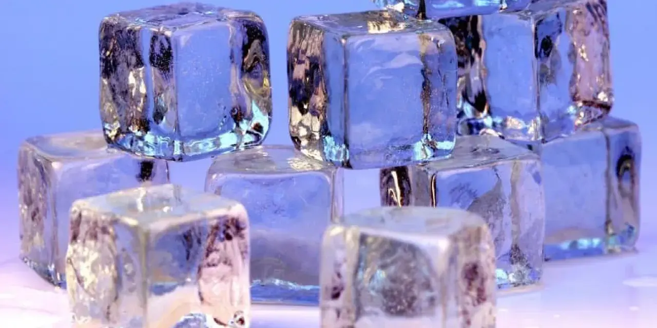 Eiswürfel stapeln sich, glitzernd und durchscheinend. Sie zeigen, wie kalt Eis werden kann, mit gefrorenen Einschlüssen und scharfen Kanten.