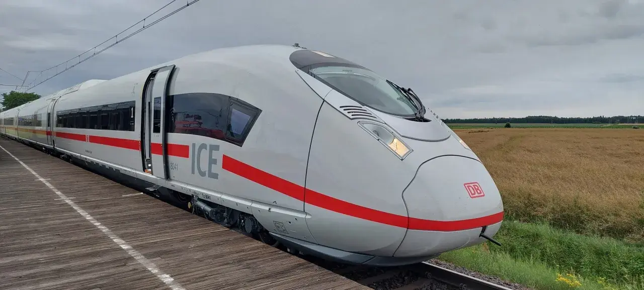 Nowoczesny, biały pociąg ICE 3neo z czerwonym pasem, stojący na peronie.