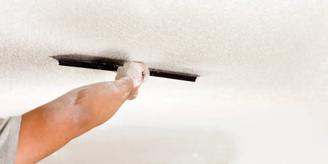 A dusty hand uses a trowel to texture a ceiling, demonstrating how to texture a ceiling for a fresh look.