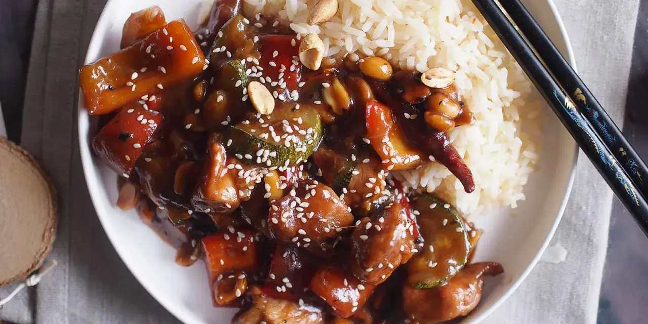 Pyszne danie kung pao z kurczakiem, warzywami i orzeszkami ziemnymi, podane z ryżem.