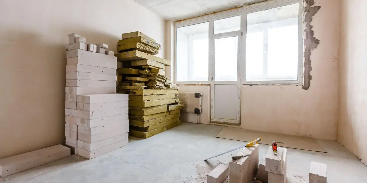Materiały budowlane, w tym pustaki i wełna mineralna, czekają na **ocieplenie ścian od wewnątrz**.