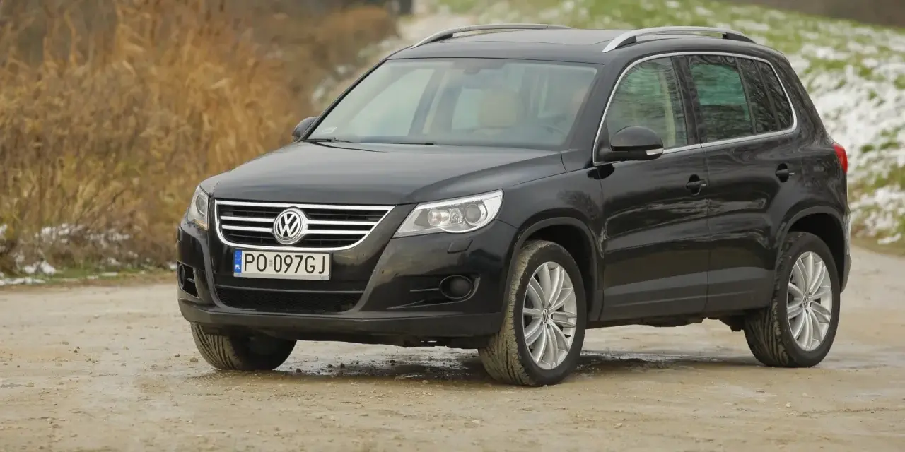 Czarny Volkswagen Tiguan, jeden z najmniej awaryjnych SUV-ów 10 letnich, na drodze gruntowej.
