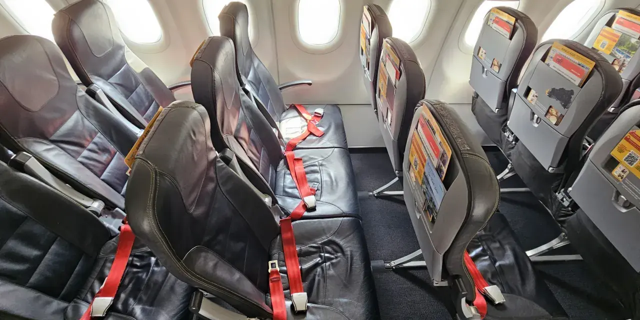 Puste fotele w samolocie, czerwone pasy bezpieczeństwa. Czy warto lecieć Pegasus Airlines? Opinie pasażerów są różne.