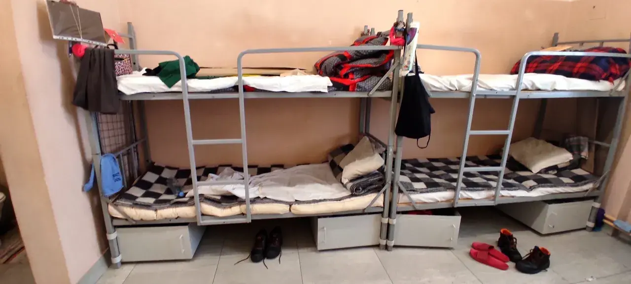 Tak wygląda dzień w areszcie śledczym: piętrowe łóżka, koce, poduszki i buty na podłodze.