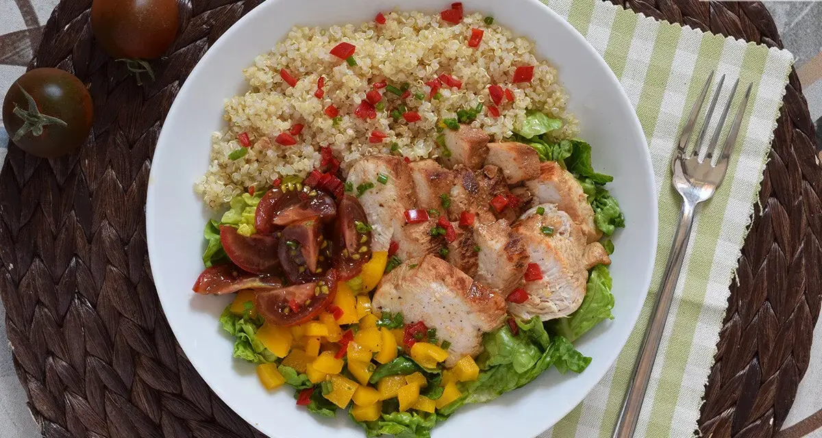 Bowl con quinoa, pollo a la plancha, tomates y mango. Un plato ideal de alimentos saciantes para adelgazar.