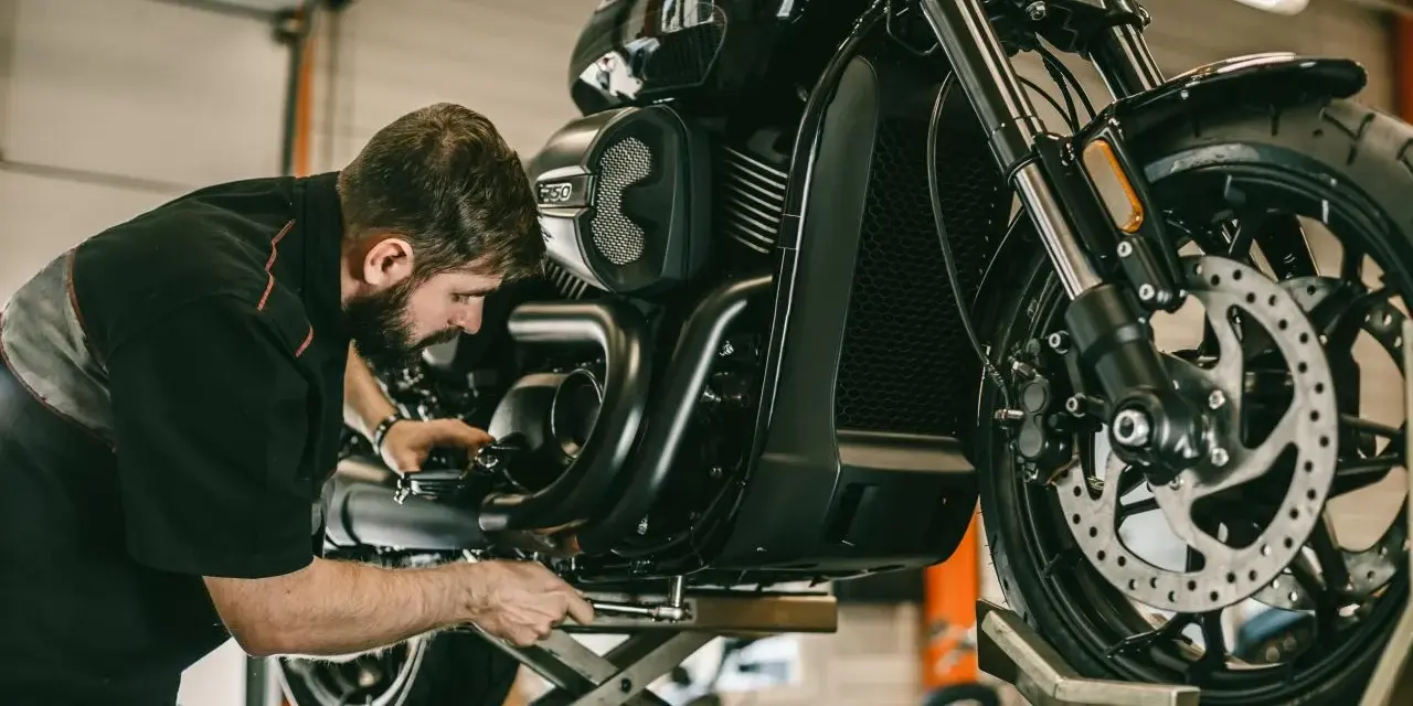 Meccanico al lavoro su una moto. Per sapere i tagliandi Ducati ogni quanti km, consulta il manuale.