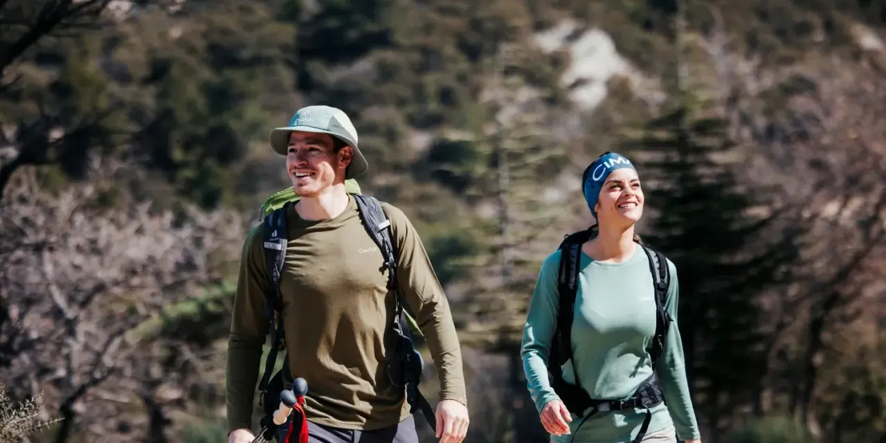 Randonneurs souriants malgré la chaleur, le mal de tête guette peut-être. Ils marchent sur un sentier rocailleux.