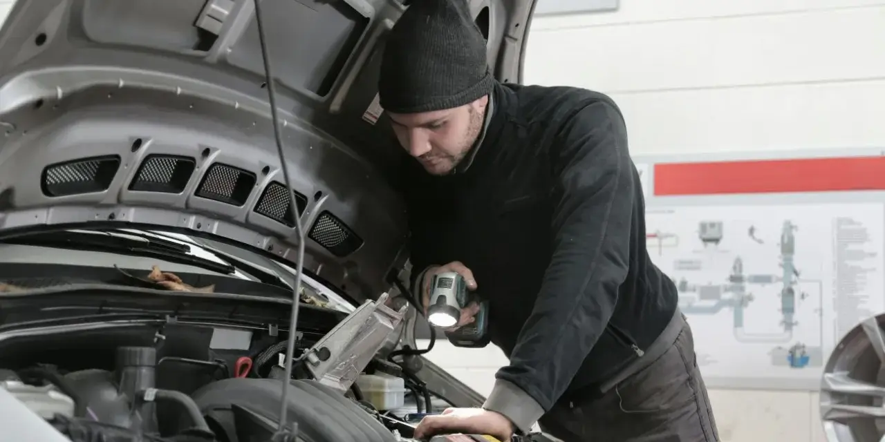 Mechanik z latarką bada silnik Forda, szukając przyczyny błędu DTC P0380.