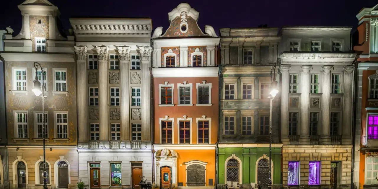 Nocny widok na kolorowe kamienice Starego Rynku w Poznaniu, przypominające urokliwe osiedle warszawskie.