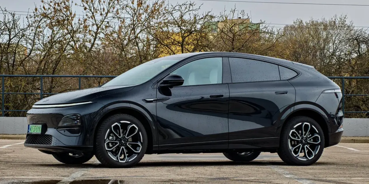 Elegancki, czarny Xpeng G6 stoi na parkingu, odbijając się w kałużach.
