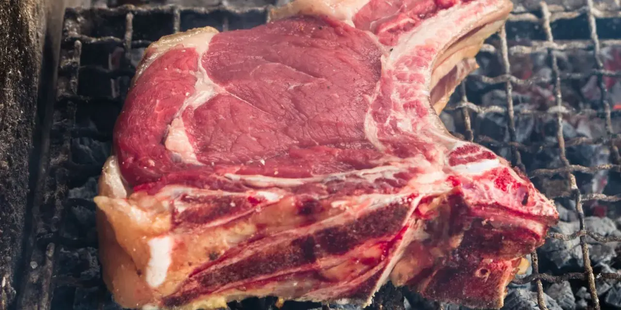 Bistecca alla fiorentina cruda su griglia, pronta per la cottura. Il tempo cottura fiorentina è fondamentale per una perfetta riuscita.