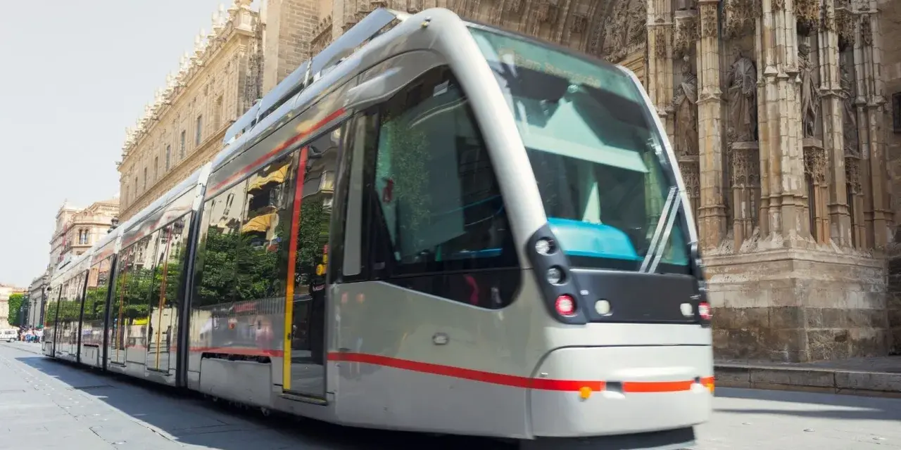 Tram moderno sfreccia davanti alla cattedrale, un modo efficiente per capire come muoversi a Siviglia.